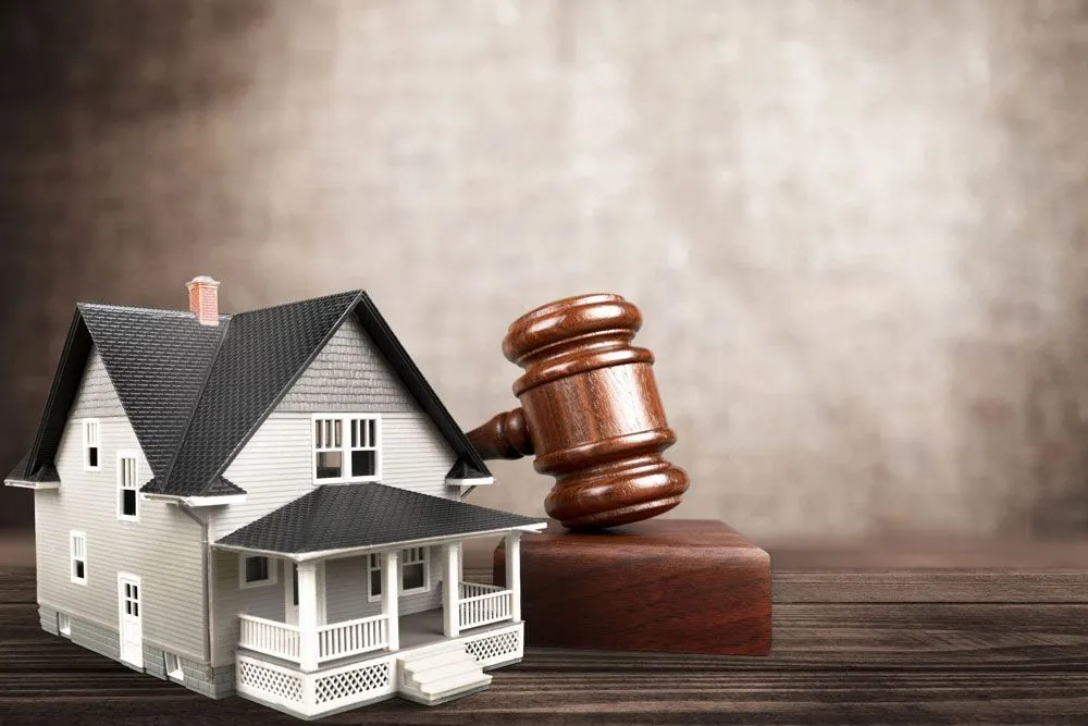 Model house beside a wooden auction gavel on a rustic table